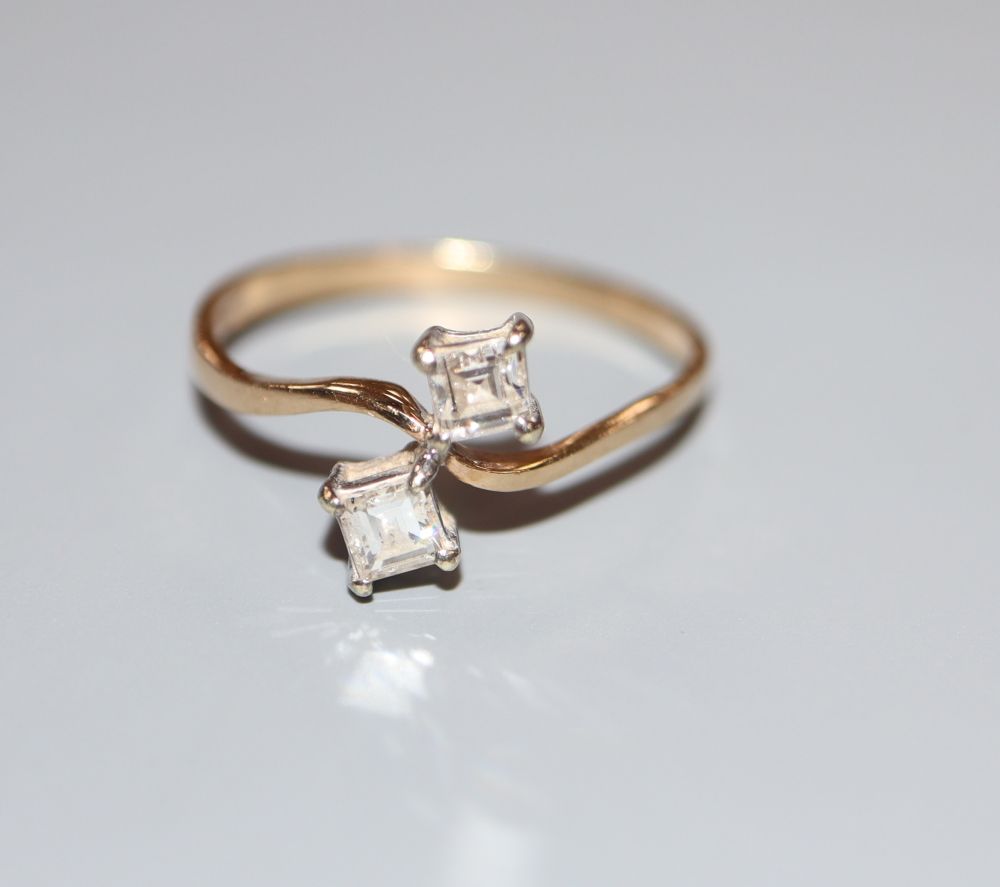 A 9ct gold and two stone square cut diamond set crossover ring, size O, gross 1.5 grams.